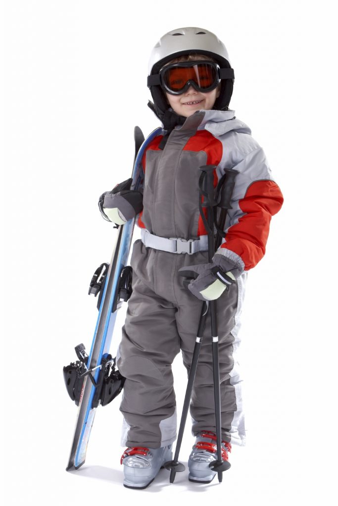 A child in a snowsuit with protective equipment ready to go skiing