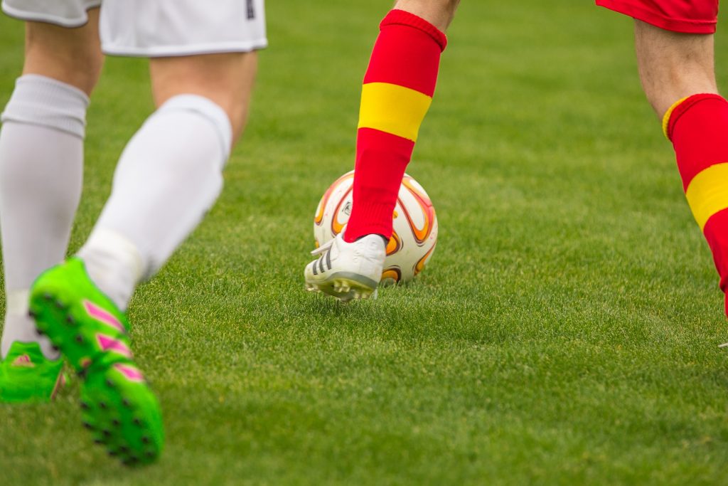 Close-up of someone dribbling a soccer ball wearing cleats