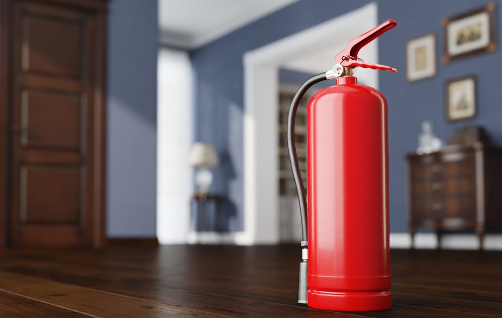 Close-up of a fire extinguisher sitting on the floor of an apartment