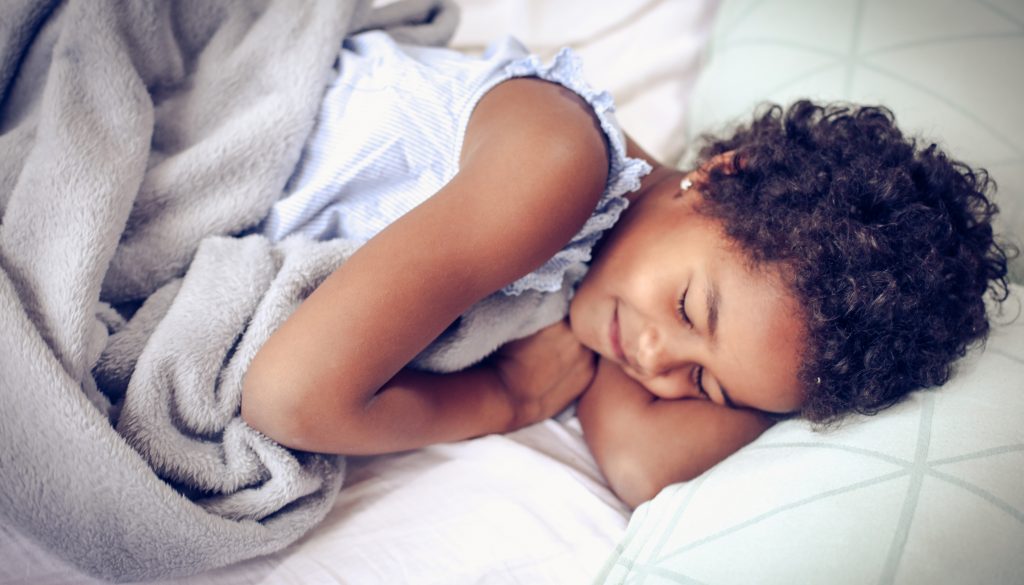 Close-up of a girl smiling while sleeping in a bed